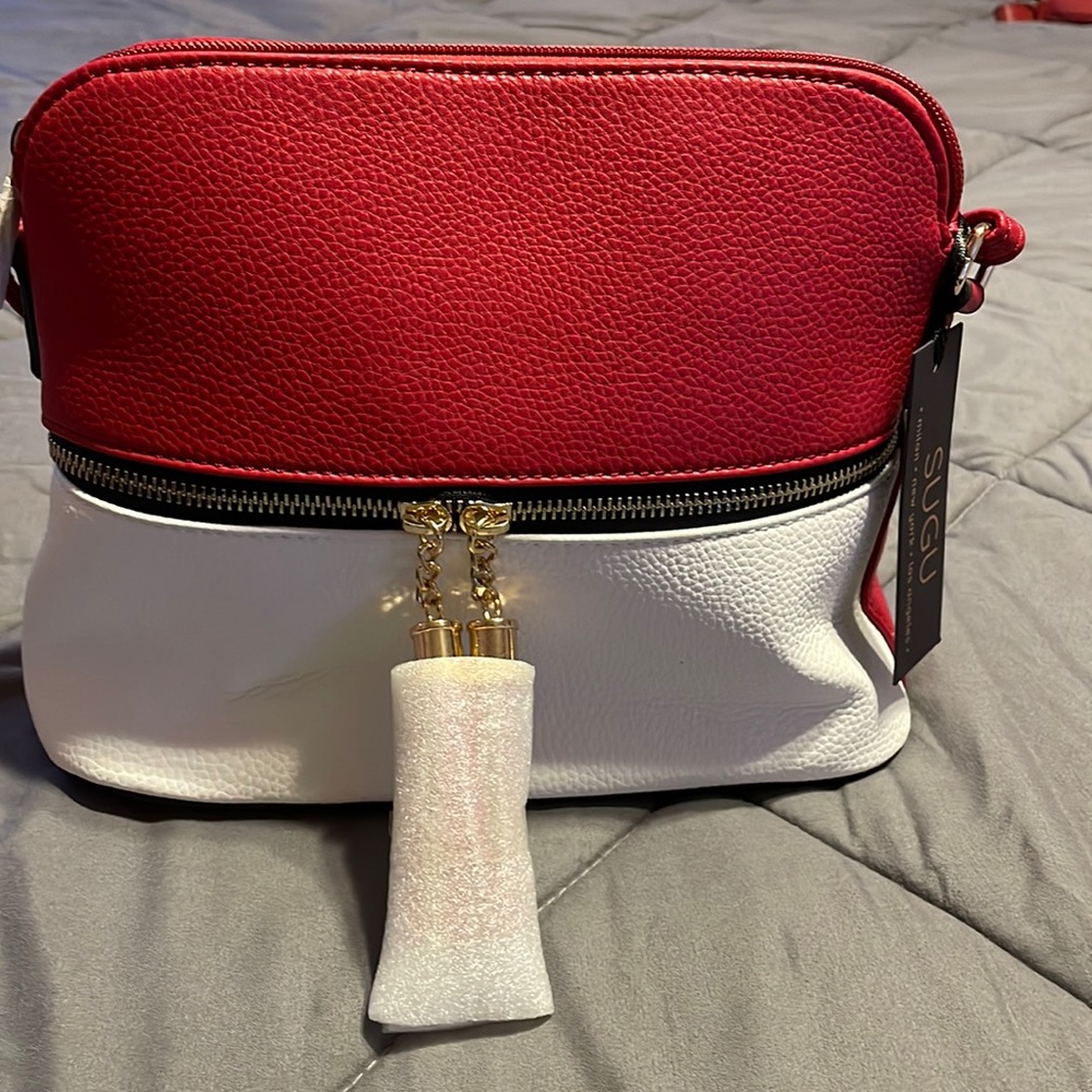 Red and white top zip handbag. Black/white striped interior with a zip pocket.